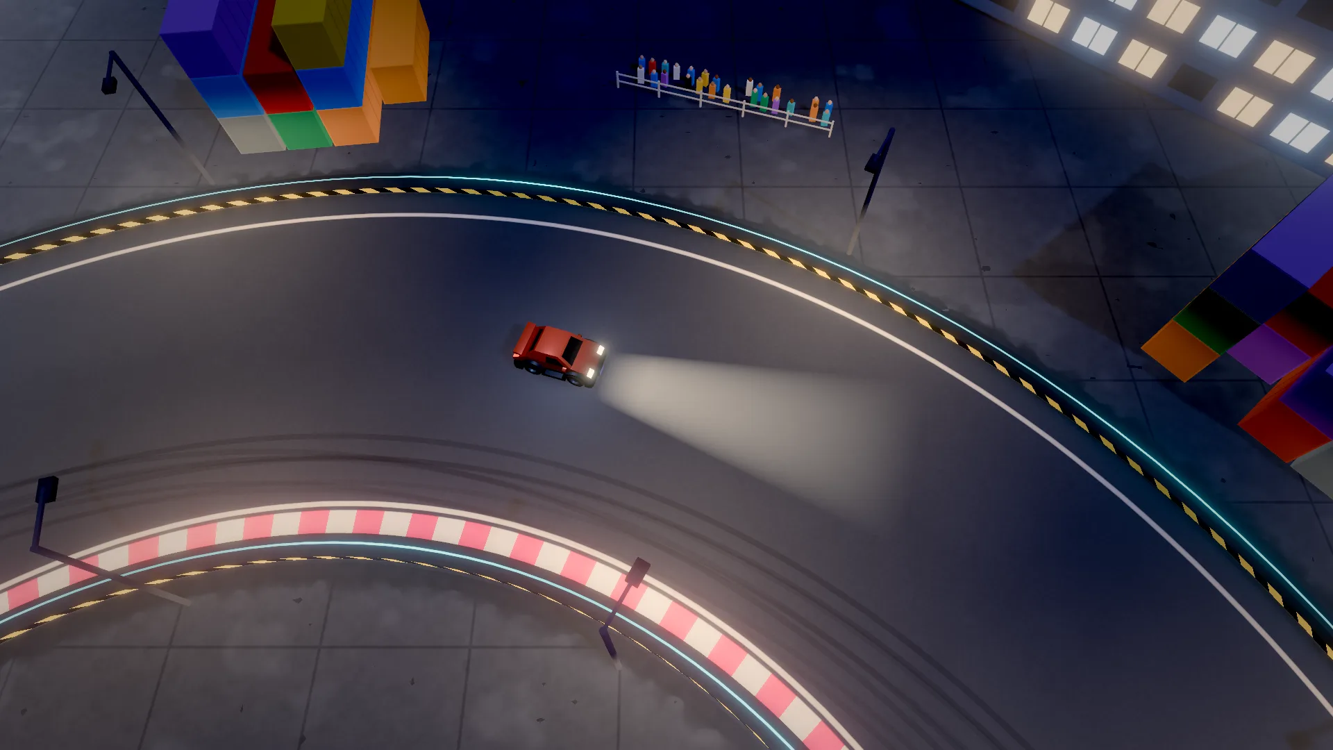 A red car drifting at night past lit office windows and stacked shipping containers, headlights on